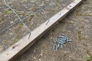 Umgebogene Drahtenden in die Löcher einschlagen, mit Stahlkrampen fixieren.